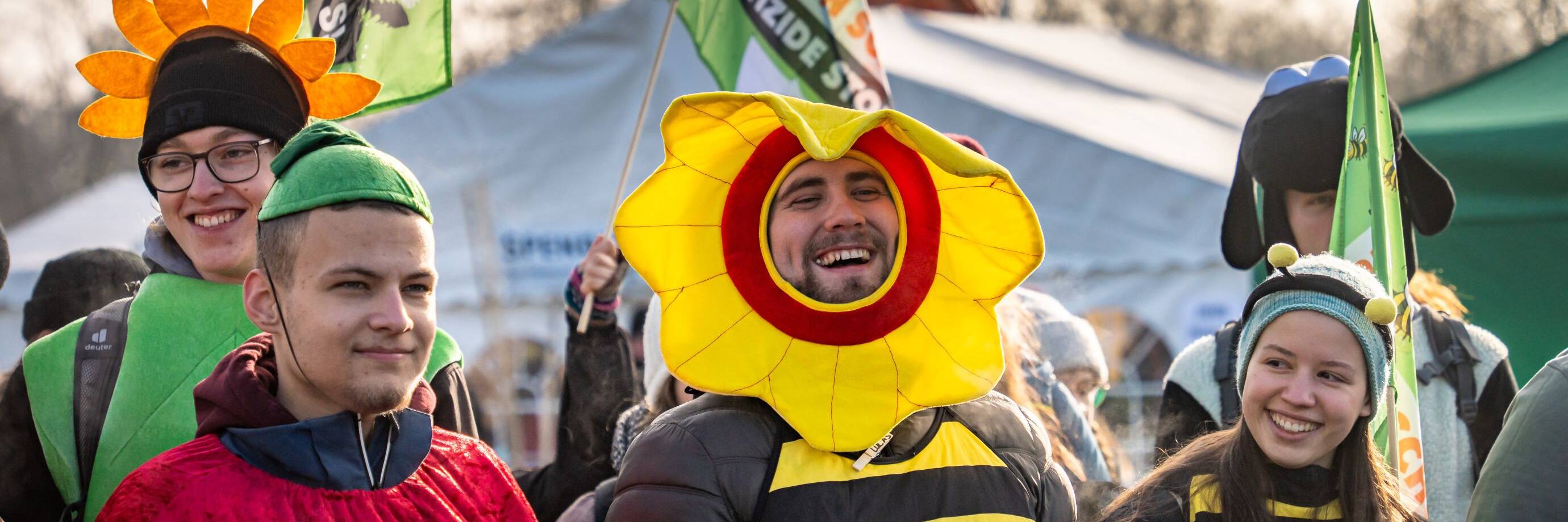 Kostümierte Menschen bei Protestveranstaltung, fröhlich und bunt.