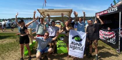 Gruppe feiert mit BUNDjugend-Banner im Freien.