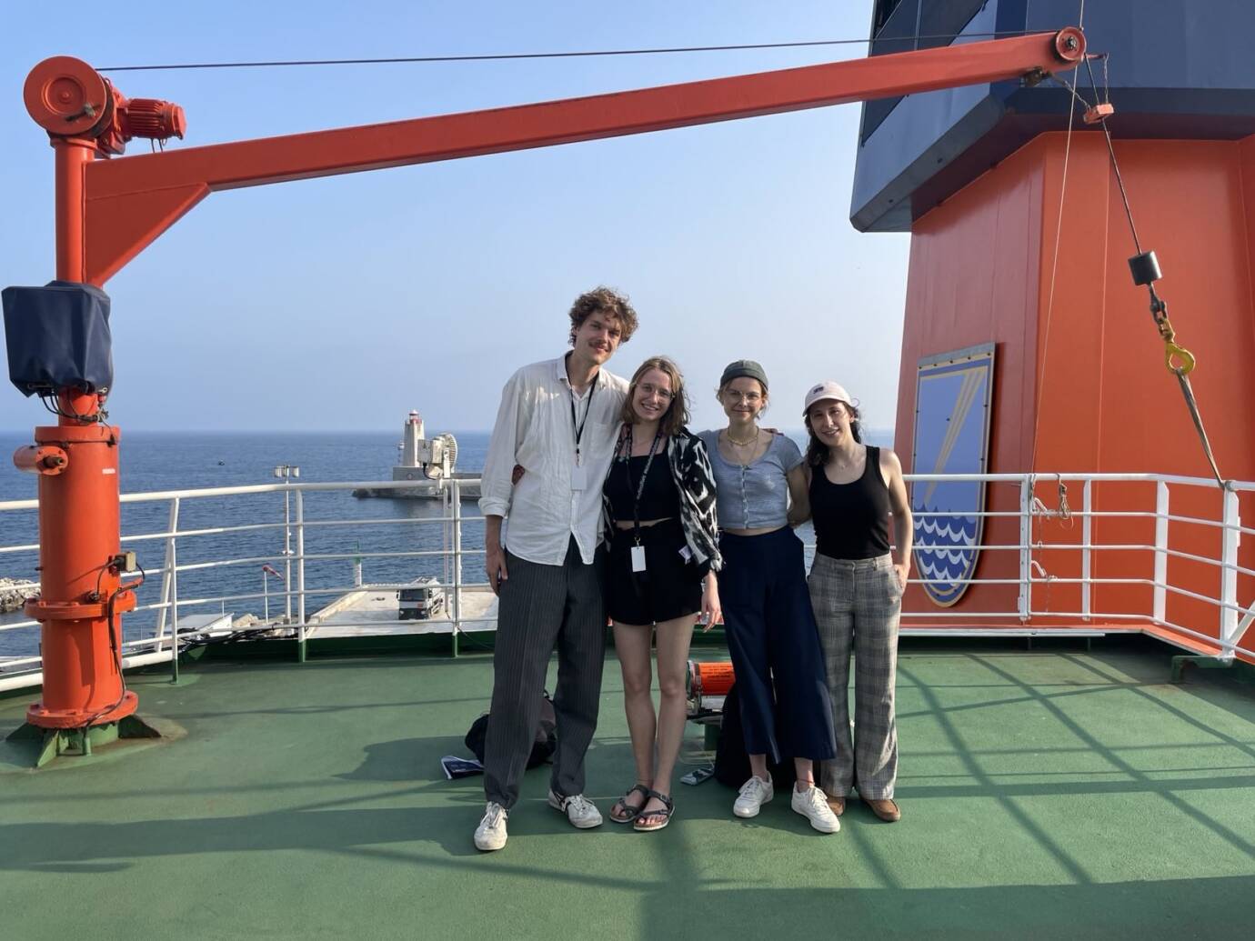 Vier Personen auf einem Schiffdeck am Meer