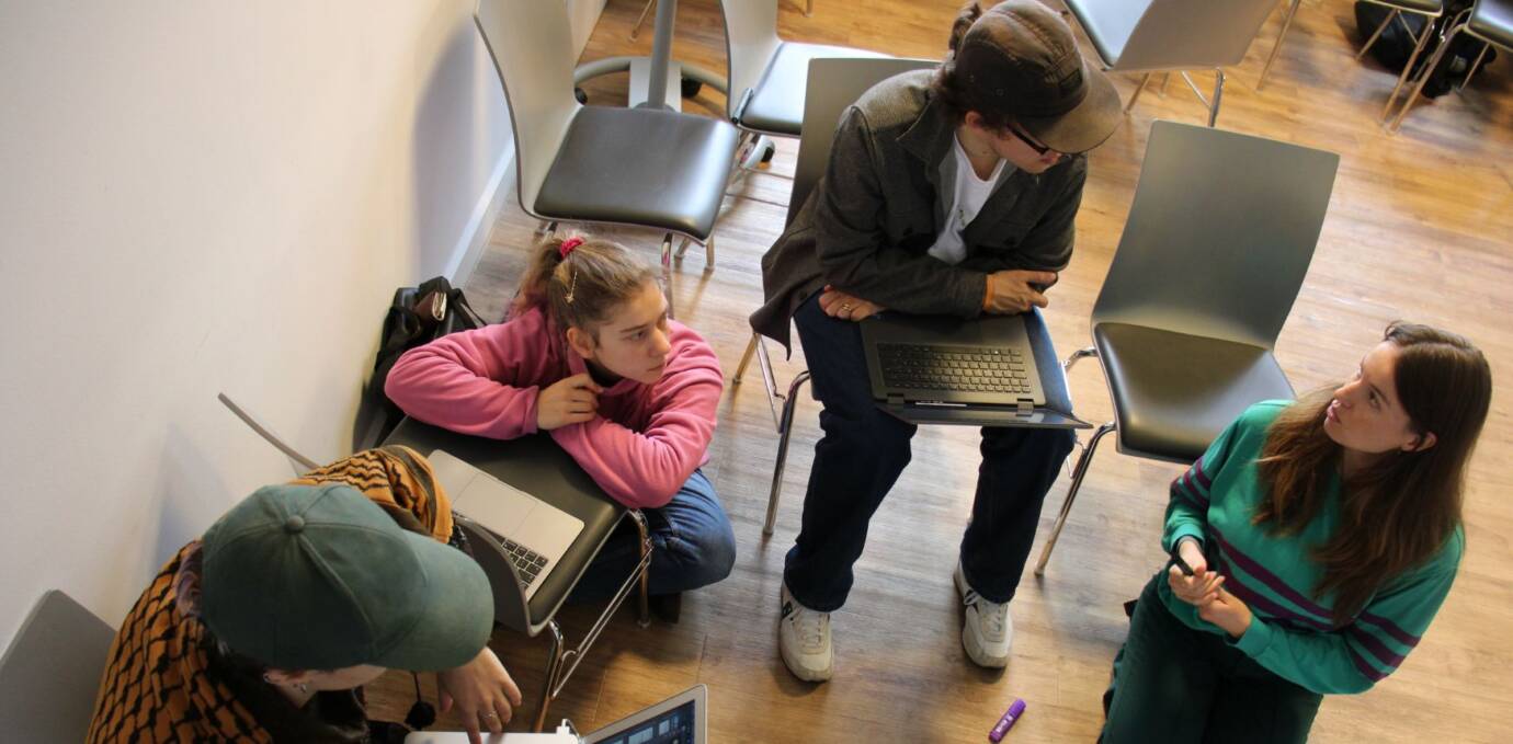 Menschen diskutieren in Gruppe mit Laptops.