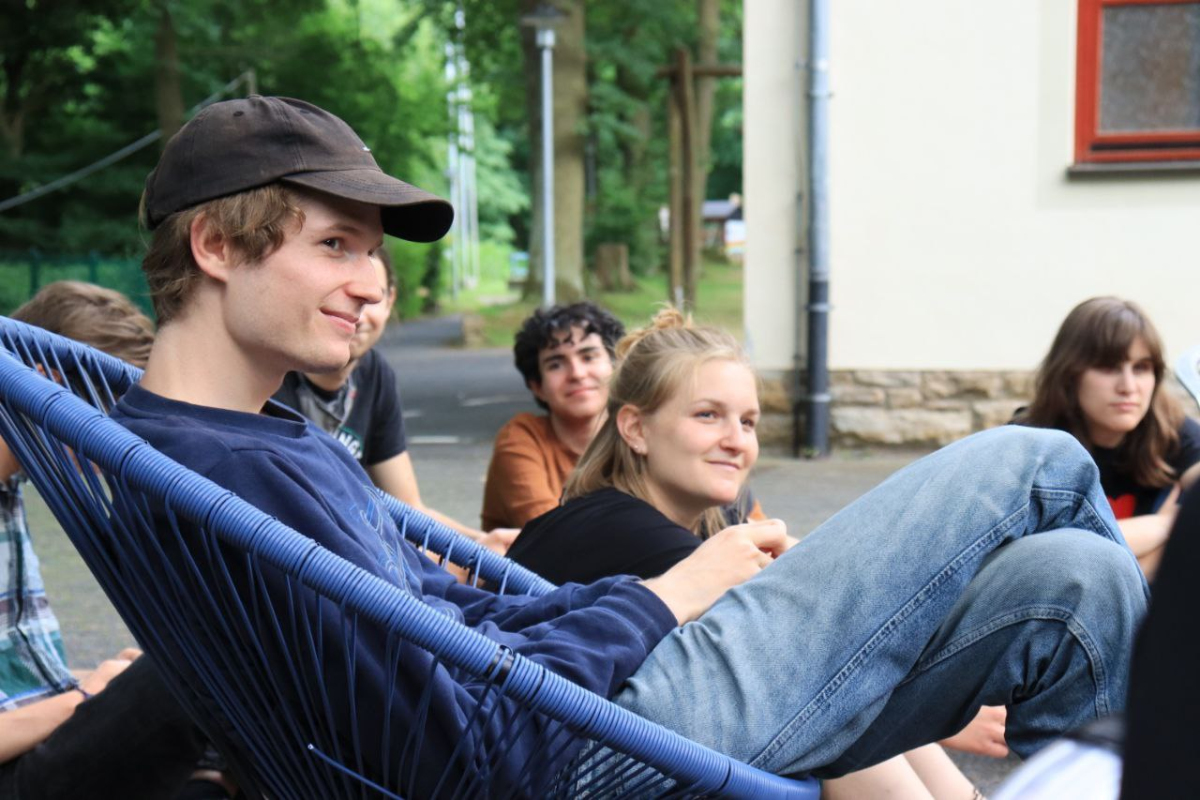 Junge Leute sitzen entspannt draußen zusammen.