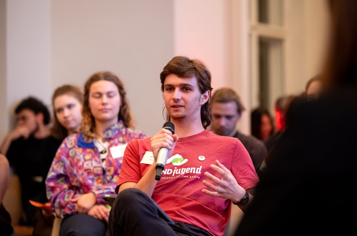 Person spricht mit Mikrofon in Diskussion.