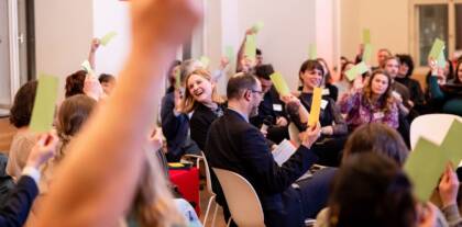 Menschen halten bunte Karten in einem Meeting hoch.